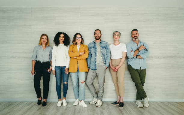 istock Group of creative businesspeople standing against a wall 1389862253