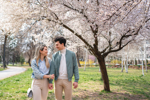 istock Lovely Caucasian couple holding hands while walking through public park 1389863909