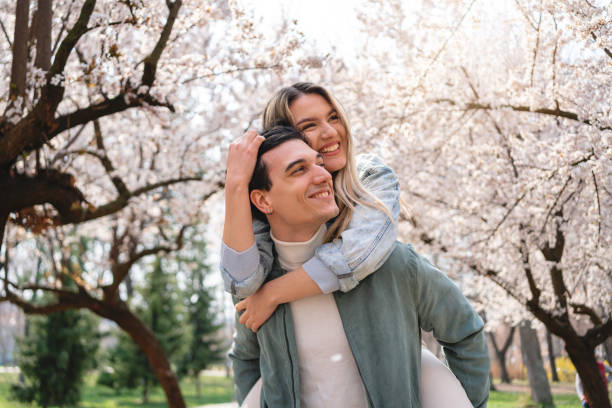 istock Joyful girlfriend piggyback her boyfriend, while both enjoy spring day 1389863965