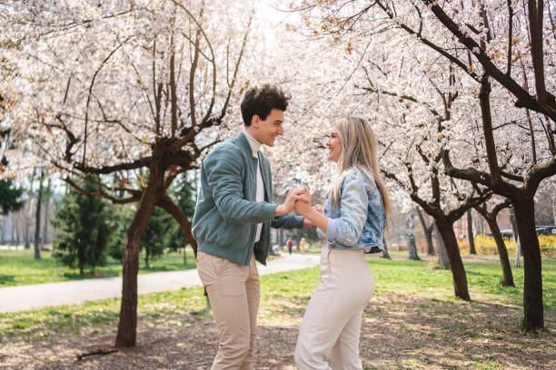 istock Playful Caucasian couple holding hands while walking through public park 1389864007