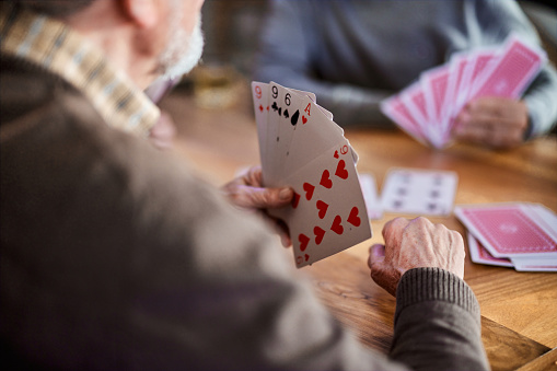 Close up of unrecognizable senior man playing cards at home.