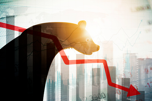 Double exposure of bear with declining stock market chart and cityscape background
