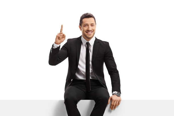 istock Businessman sitting on a blank panel and pointing up 1389866794