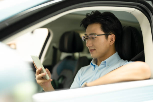 istock Young Asian man  using smart phone and enjoying new car. 1389868244