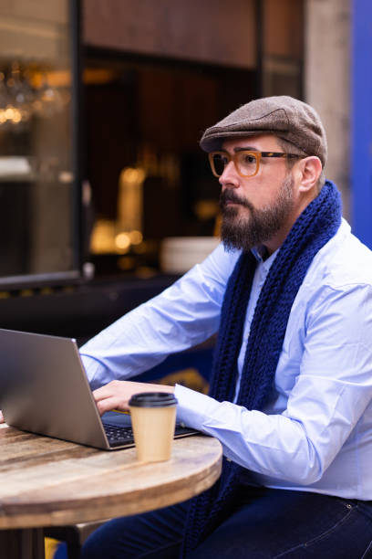 istock Thoughtful tourist using his laptop in outdoor cafe 1389868295