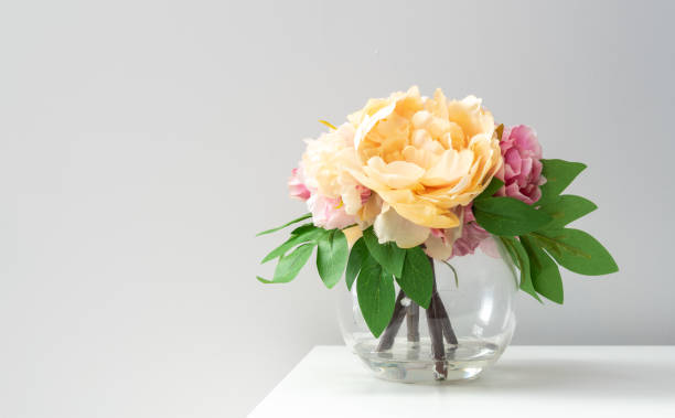 a bouquet of imitation flowers in a glass vase - small bouquet imagens e fotografias de stock