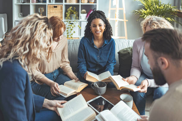 istock Small group of people with a mixed age range talking and laughing while having a book club meeting 1389869858