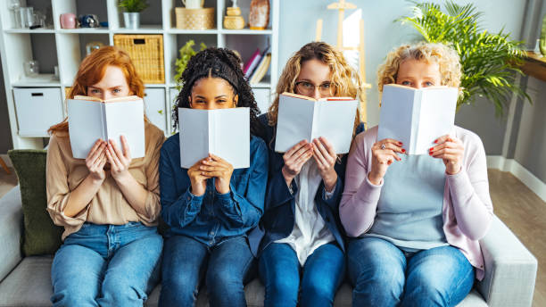 Females reading with books obscuring faces