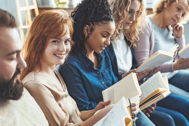 istock Young woman holding book in her hands while looking at camera. 1389869911