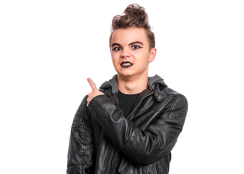 Portrait of teen boy student with spooking make-up, isolated on white background. Teenager in style of punk goth dressed in black laughing and pointing fingers. Problems of transitional age