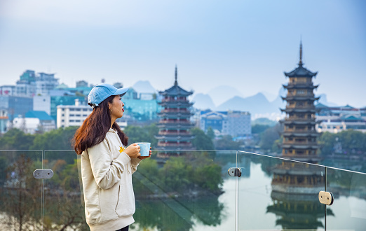 Young women drinking coffee and looking at Pagodas in downtown of Guilin, China