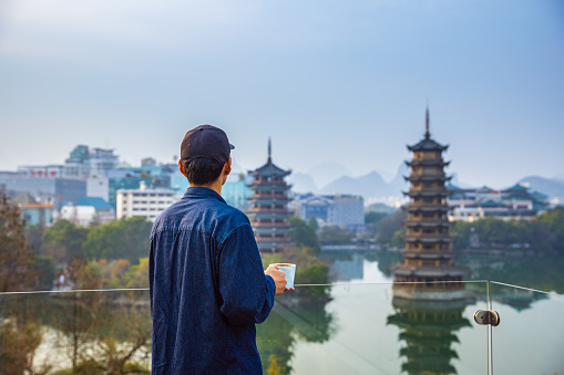 Men drinking coffee and looking at Pagodas in downtown of Guilin, China