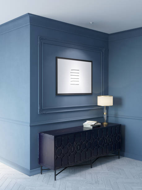 istock Classic interior in blue tones with an illuminated horizontal poster above an old black cabinet with a lamp and books on it, white parquet flooring, moldings on the walls. 1389872367