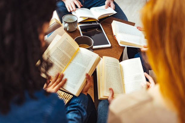 estudiantes adultos que estudian juntos en la biblioteca - literature fotografías e imágenes de stock