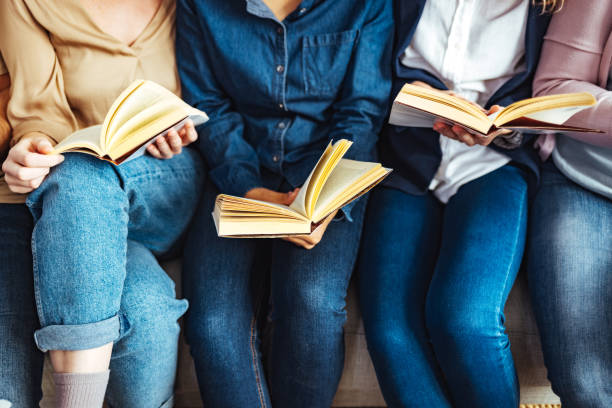 groupe diversifié d’amis discutant d’un livre à la bibliothèque. - smart casual cheerful content image photos et images de collection