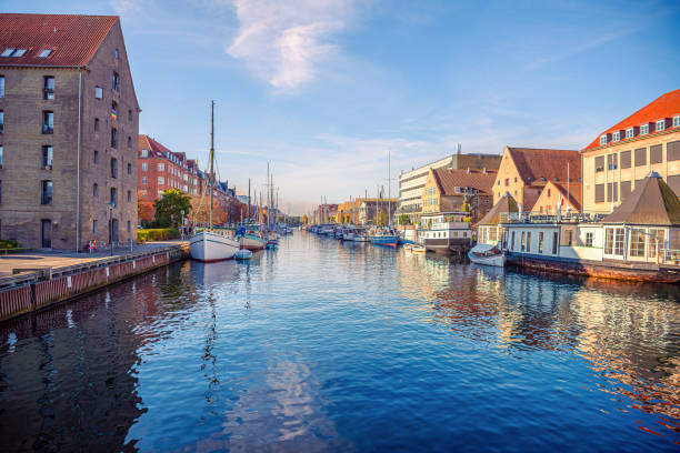 river canal with many boats and ships with small old houses in the  neighbourhood area christianshavn in copenhagen, denmark - denmark copenhagen brick street imagens e fotografias de stock