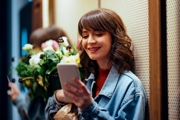 istock Smiling Woman with Dental Braces Using her Mobile Phone in the Elevator 1389882672