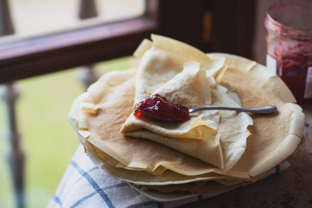 Thin crepes and strwberry jam served on a plate. Rustic style.