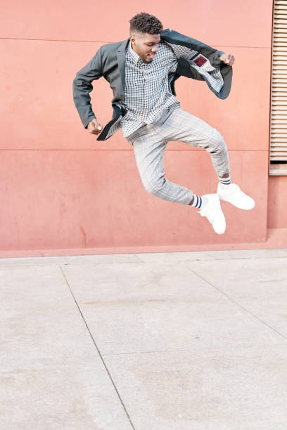 portrait en pied d’un homme afro-américain joyeux sautant isolé sur un fond rouge - hip hop hipster afro men photos et images de collection