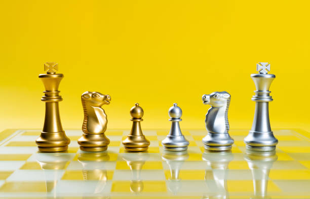 Golden and silver chess pieces on chess board.