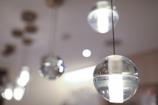 Close-up of round shaped lamps. Lights on ceiling. Modern interior design in apartment. Luminaire made of glass material. Cozy light in room. Renovation concept