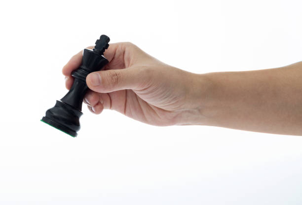 Human hand holding chess king on white background.