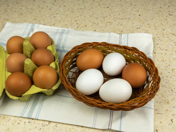 istock Chicken eggs in cardboard box and in wicker basket on classic table napkin with selective focus.Copy space. 1389885902