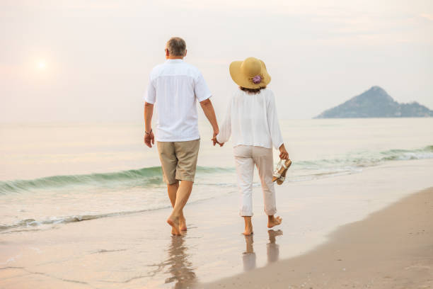 istock Active senior couple walking on the beach 1389890141