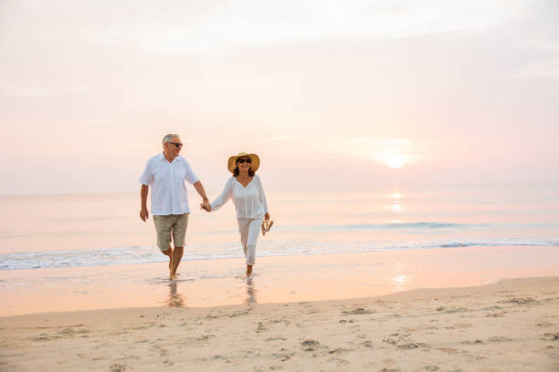 istock Active senior couple walking on the beach 1389890202