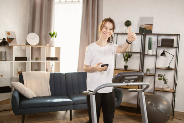 istock Front view image of a sporty woman using a smartphone while doing an exercise on the treadmill 1389890411