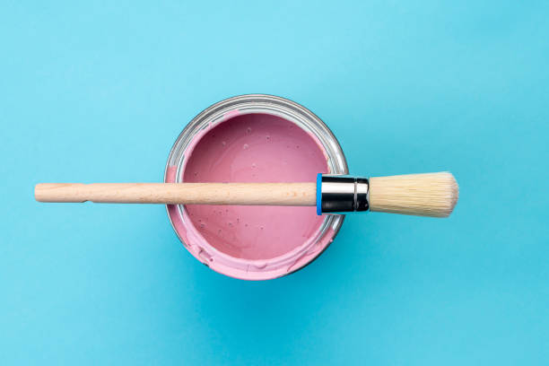 istock Brush on open can of pink paint on blue pastel background 1389892030