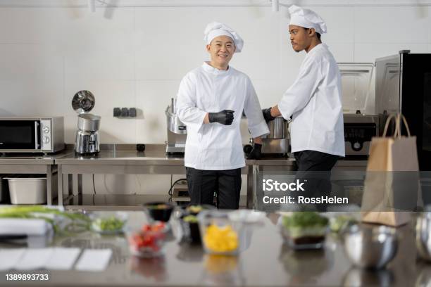 Two Chef Cooks Standing Together In Professional Kitchen Stock Photo - Download Image Now