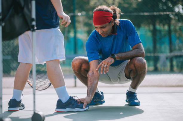istock Asian Tennis Coach Trainer squatting adjusting his student feet position for better posture 1389895672