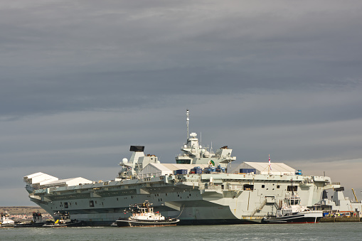 Royal Navy aircraft carrier HMS Elizabeth moored at dockyard in Portsmouth,Hampshire, England. With attending tugs.