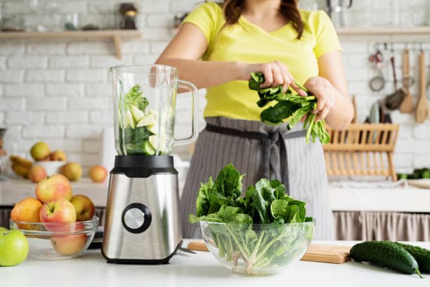 istock Young woman making green spinach smoothie at home kitchen 1389896815