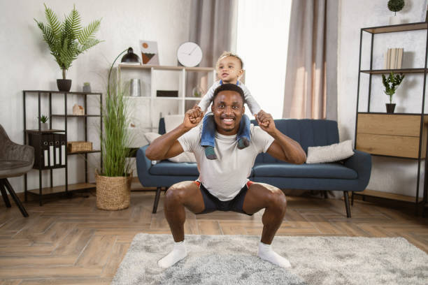 istock Small son sit on strong dad shoulders doing squat exercises. 1389896973