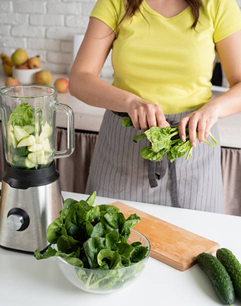 istock Young woman making green spinach smoothie at home kitchen 1389896977