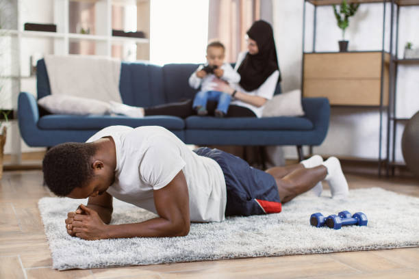 リビングルームでトレーニングをしながらヨガの板をやっているアフリカ系アメリカ人の男性にフィット - yoga business women living room ストックフォトと画像