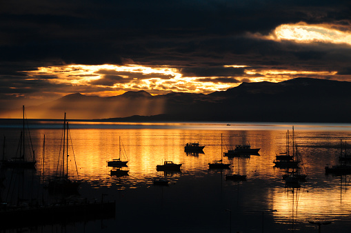 Golden sunset over the sea with silhouette of boats near the bay