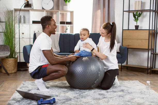 リビングルームでのスイスボールでの幸せなフィットネス家族のトレーニング。 - yoga business women living room ストックフォトと画像