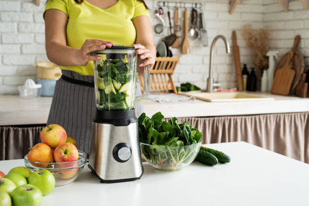 istock Young woman making green smoothie at home kitchen 1389898122