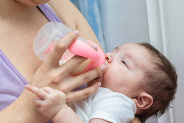 istock beautiful latina baby making an obscene gesture with her middle or middle finger, while taking her bottle and trying to fall asleep in her mother's arms. 1389899467