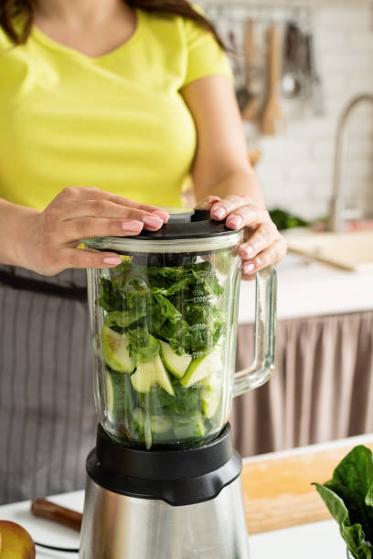 istock Young woman making green spinach smoothie at home kitchen 1389900150