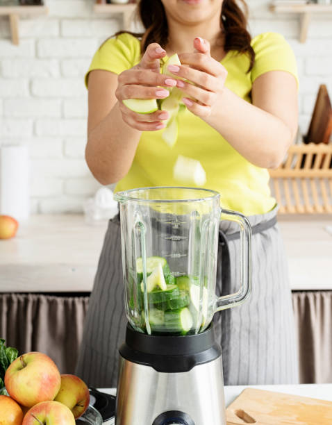 istock Young woman making green cucumber smoothie at home kitchen 1389901991