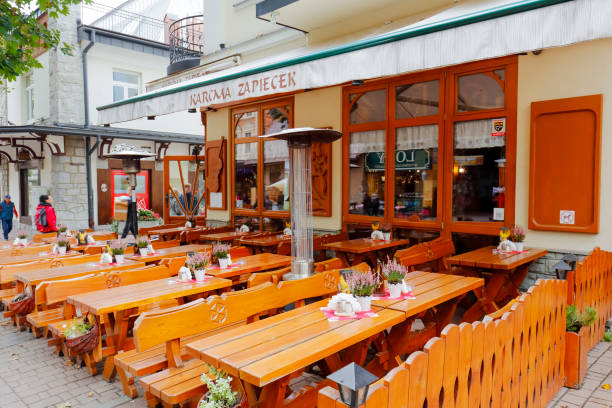 Zakopane, Poland - September 20, 2016: Tables and benches belonging to an outdoor restaurant called Zapiecek await guests. It is located on Krupowki Street, which is the main promenade of the city.