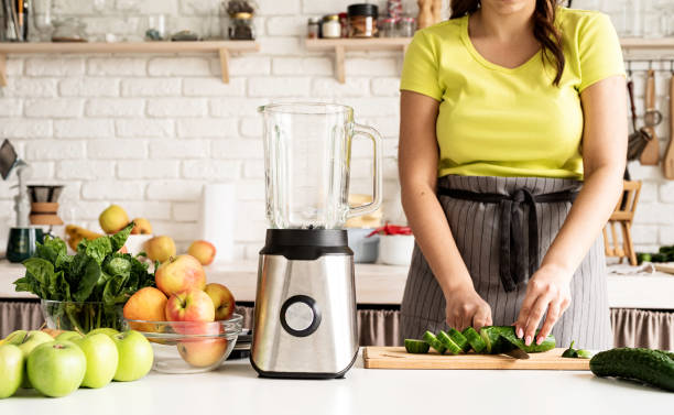 istock Young woman making green smoothie at home kitchen 1389902454