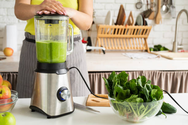 istock Young woman making green smoothie at home kitchen 1389902786