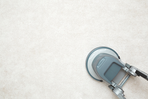 Gray professional disc machine on light beige carpet background. Closeup. Foaming and brushing equipment. Commercial cleaning service. Empty place for text. Top down view.