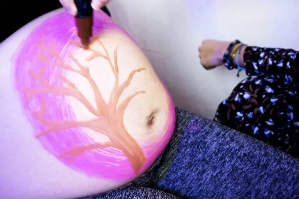 Body painting on the belly of an eight month pregnant woman. No copy space