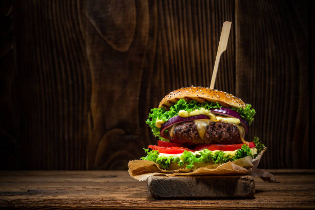 Tasty Big Burger in Bun on Wooden Background with Copy Space stock photo